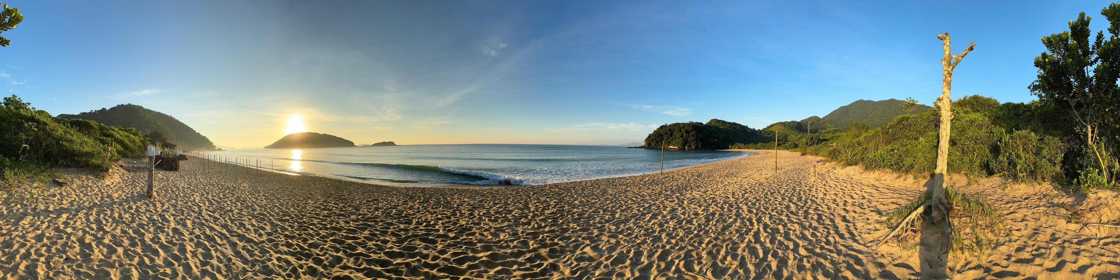 Une plage offrant une vue dégagée sur l’océan, un rivage sablonneux et une montagne en arrière-plan.