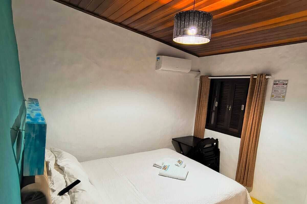 Une chambre à coucher comprenant un lit, une table de chevet, une fenêtre avec des rideaux et un luminaire au plafond.