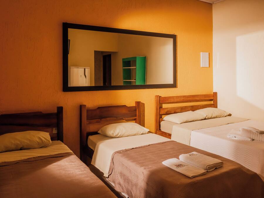 Habitación de hotel con dos camas individuales, un espejo grande y una mesita con toallas.