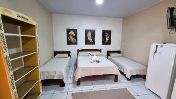A room with two single beds, a wardrobe, a refrigerator, and three wall-mounted pictures.
