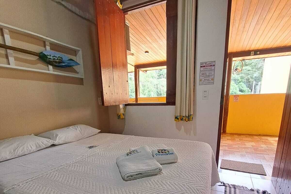 Une chambre à coucher avec un lit, une fenêtre, une porte et une étagère fixée au mur.