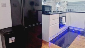 A modern kitchen with a black refrigerator, white cabinets, a microwave, and a built-in oven.
