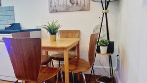 A dining area with a wooden table and chairs, a painting on the wall, and a floor lamp.