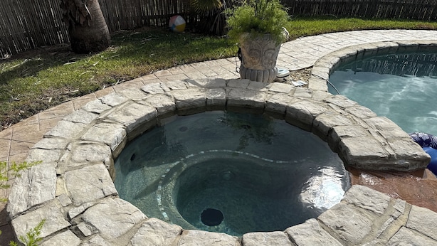 Un bain à remous bordé de pierres, entouré d’une terrasse également en pierre.