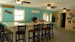 Une cuisine avec un coin bar, des ventilateurs de plafond et un carrelage au sol.
