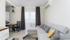 Ein modernes Wohnzimmer mit einem grauen Sofa, einem Holzesstisch, einem schwarzen Stuhl und einem kleinen Schreibtisch.