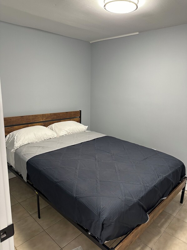 A bedroom with a single bed, white walls, and a wooden headboard.