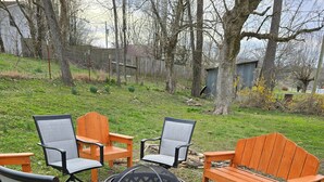 Un jardin avec un foyer, des chaises en bois et une table en bois.