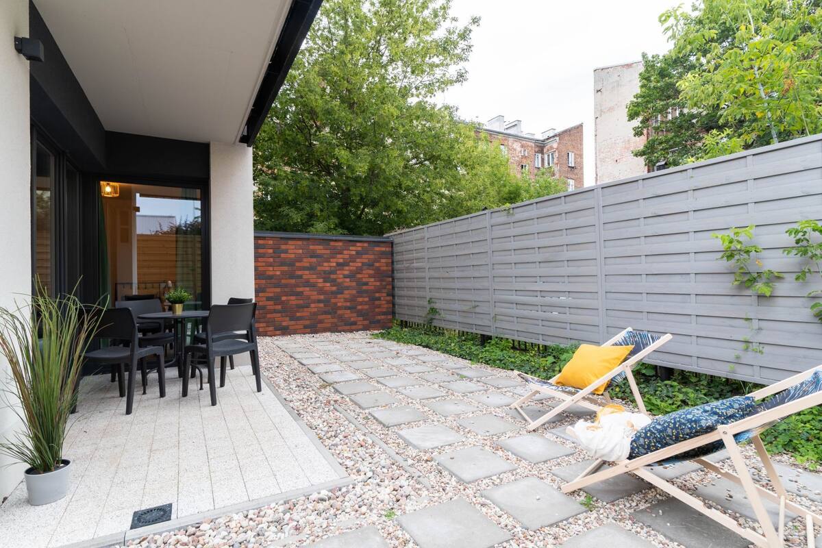 A patio with outdoor seating, a brick wall, and a wooden fence.