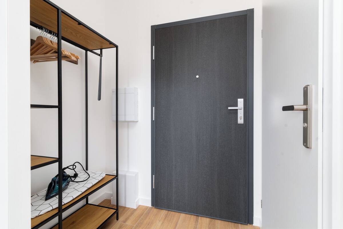 A room with a wardrobe, a bench with a bag, and a door with a handle.