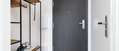 A room with a wardrobe, a bench with a bag, and a door with a handle.