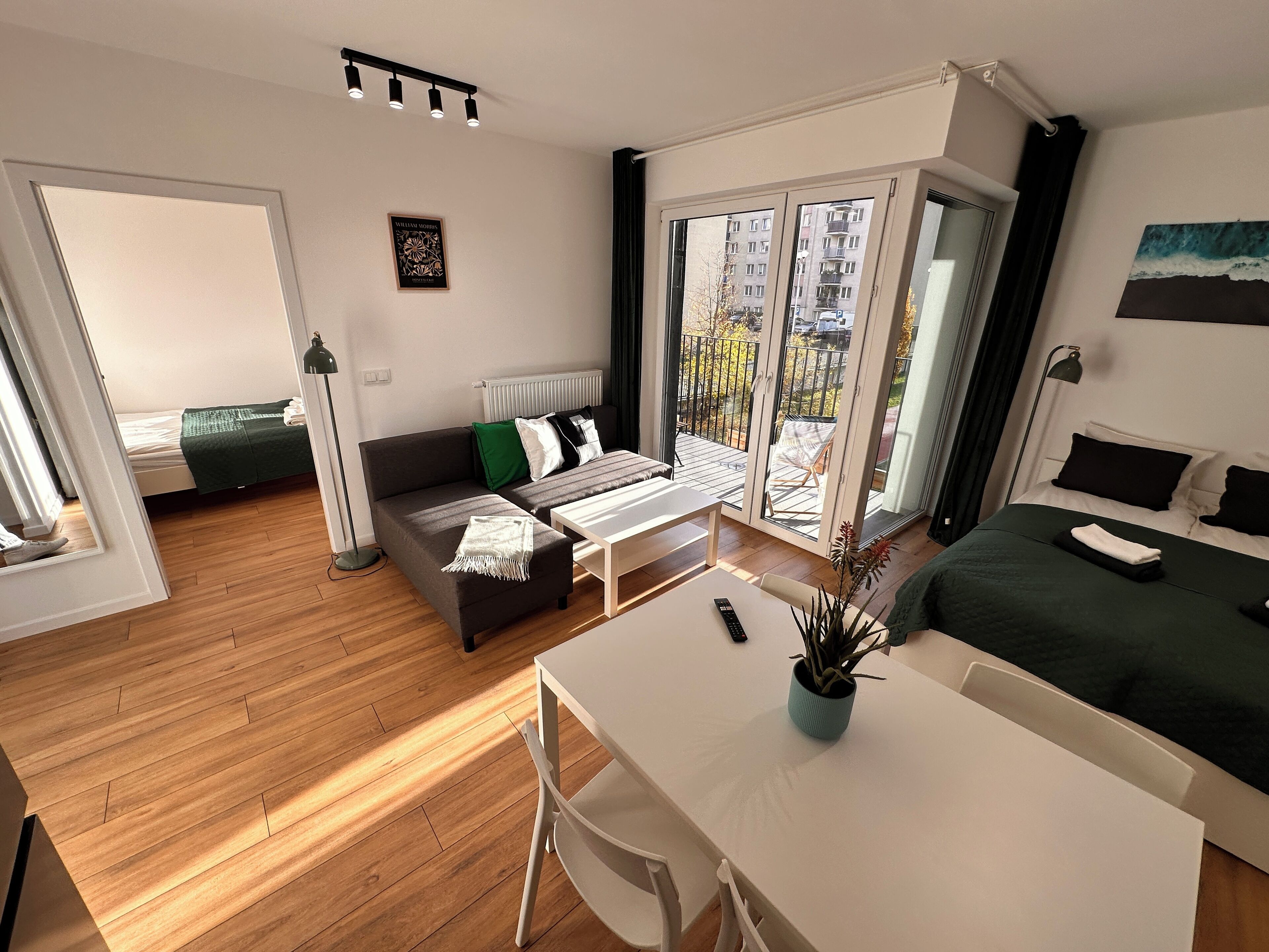 Una sala de estar moderna con un sofá, una mesa de comedor y vistas al balcón.
