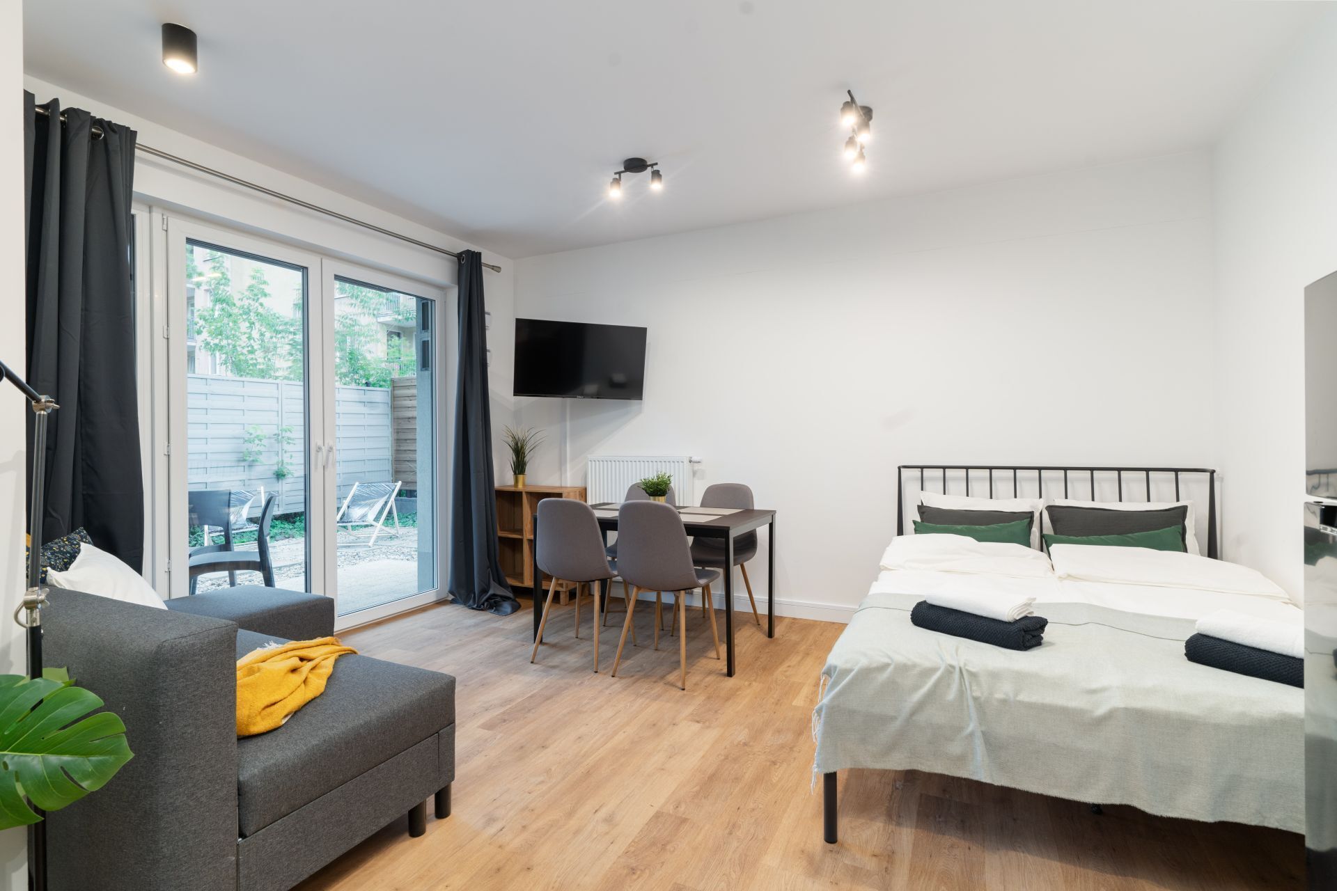 A modern bedroom with a bed, a desk, and a sofa.