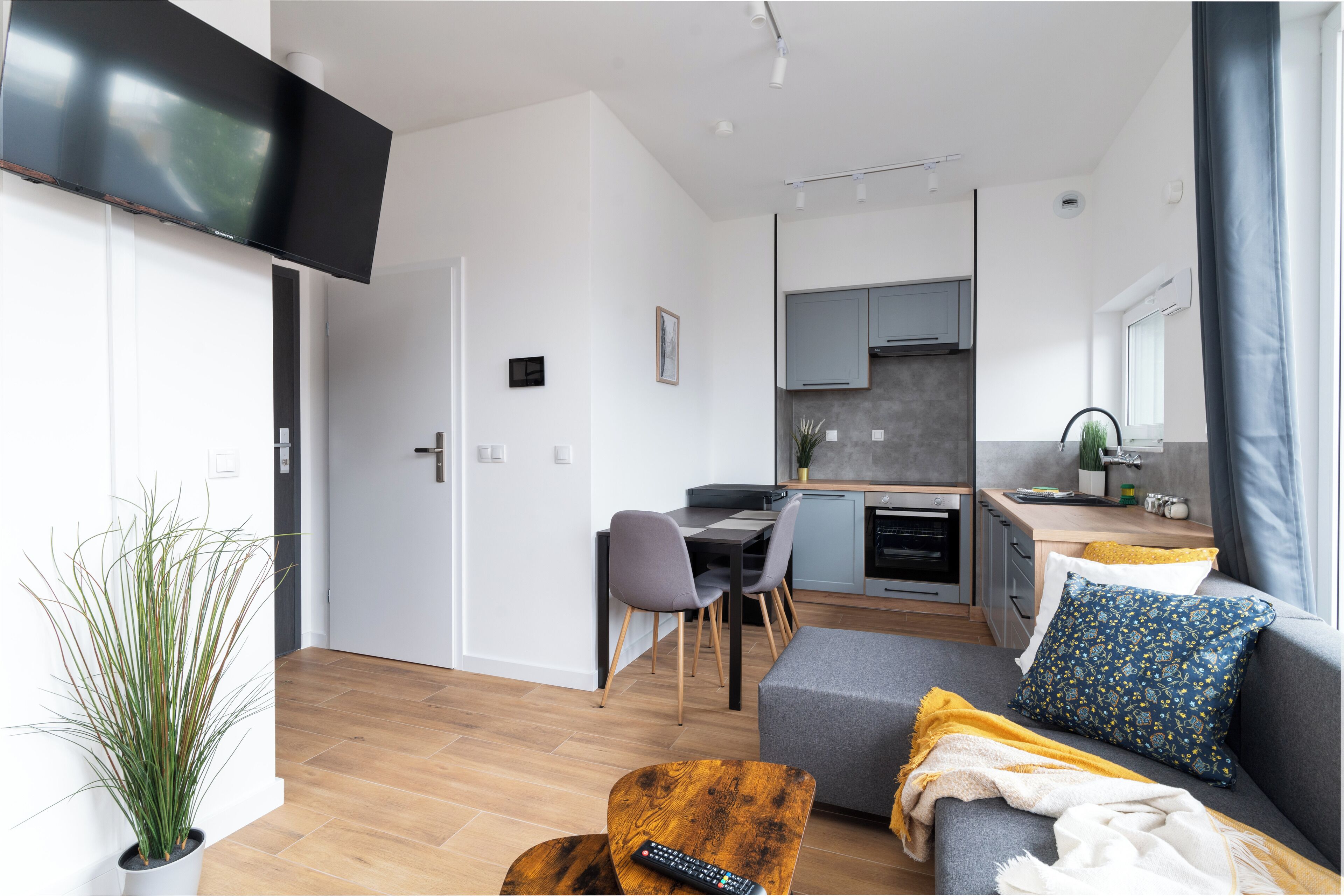 A modern living room with a sofa, a coffee table, and a TV mounted on the wall.