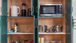 Een keuken met een magnetron, koffiezetapparaat, blender en diverse keukengerei.