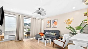 A modern living room with a sofa, coffee table, and dining area. - Peaceful Modern HNL Getaway (Honolulu)