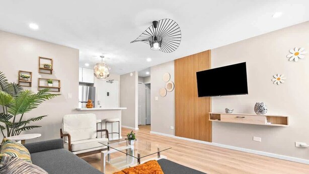 A modern living room with a sofa, a coffee table, and a TV mounted on the wall. - Peaceful Modern HNL Getaway (Honolulu)