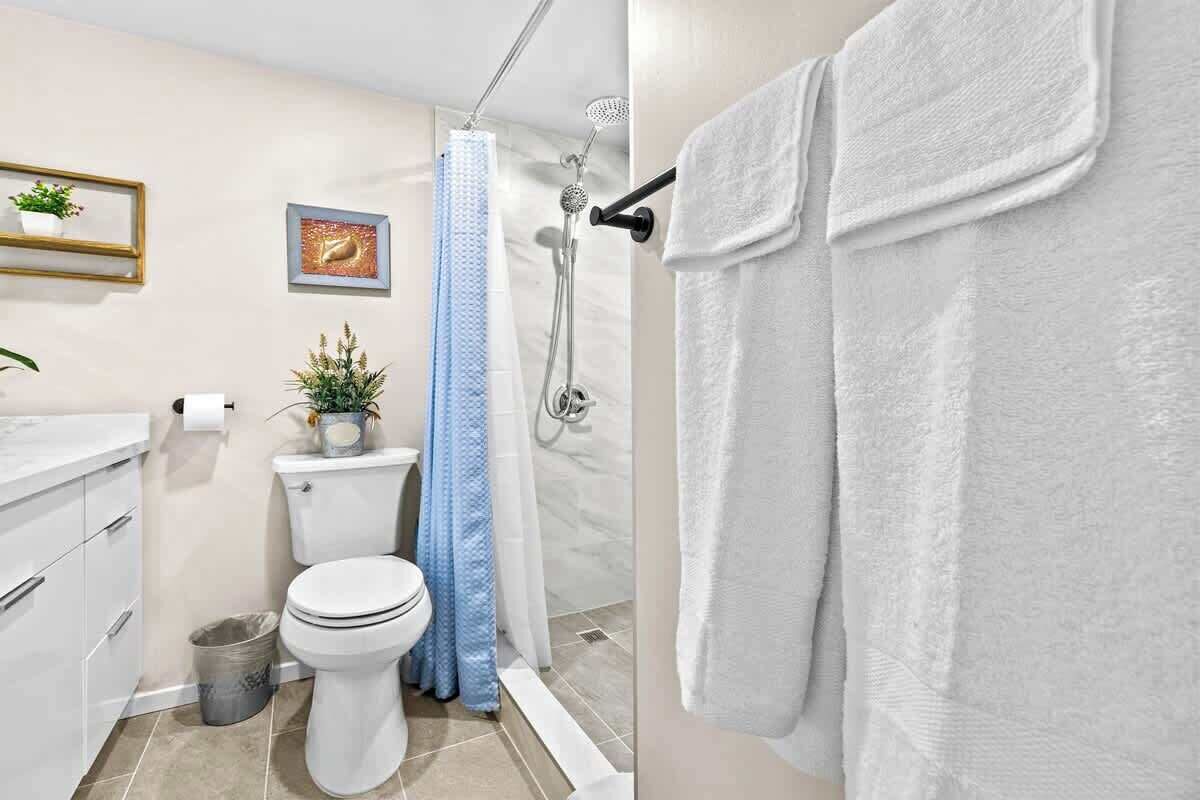 Et badeværelse med toilet, bruser og håndklædestang.