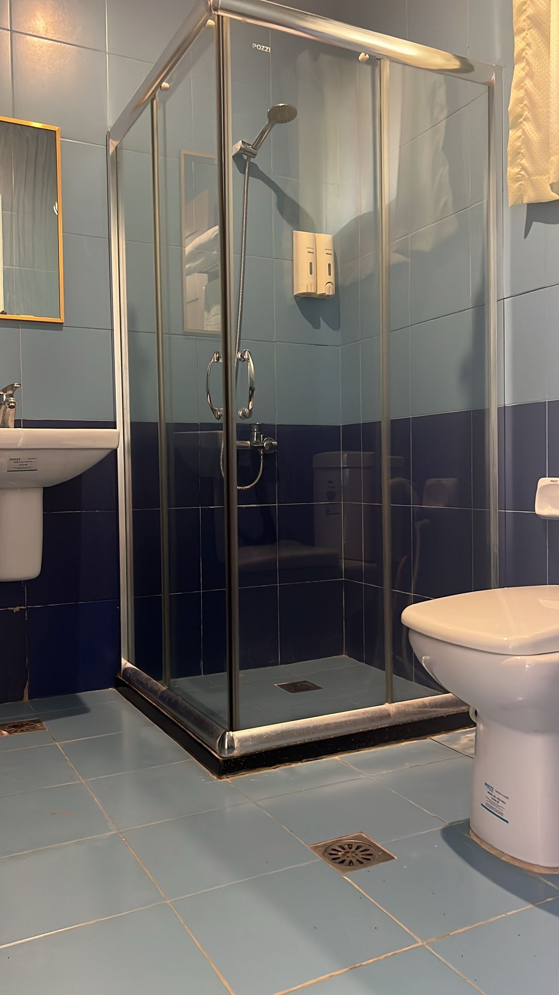Un baño con ducha de vidrio, lavamanos y retrete.