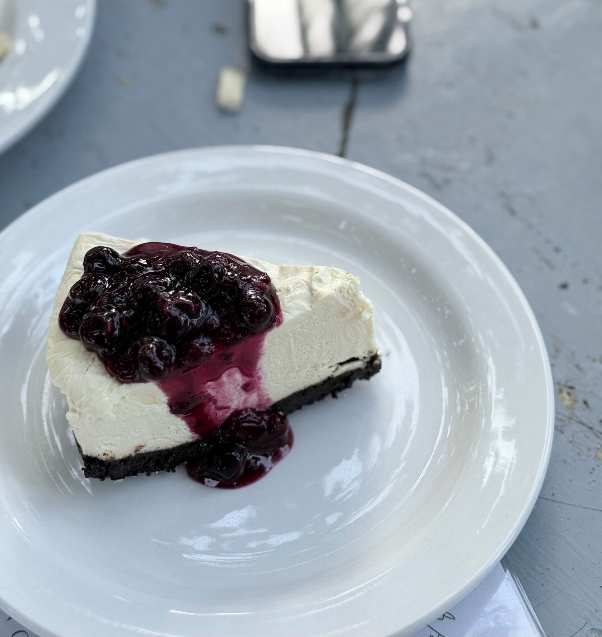 A slice of cheesecake with a cherry topping on a white plate.