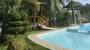 A swimming pool surrounded by palm trees and a gazebo.