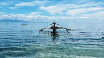 A clear view of a boat in calm waters with a distant mountain range and a clear sky.
