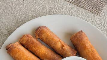Un plato de rollitos de primavera fritos con salsa para mojar.