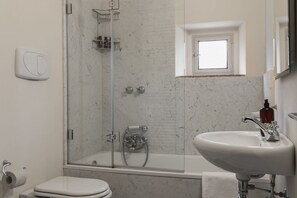 A bathroom with a toilet, a sink, and a shower area.
