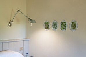 A room with a bed, a desk lamp, and four framed botanical illustrations on the wall. - Elegant Villa with private pool inside Chianti (Greve in Chianti)