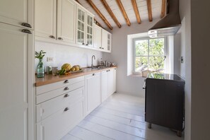 A kitchen with white cabinets, a wooden countertop, and a window providing natural light. - Charming Villa with Private Pool immersed in the greenery of Chianti (Panzano In Chianti)