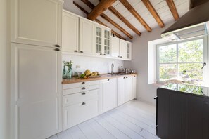 Cozinha com armários brancos, bancada de madeira e janela com vista para o verde.