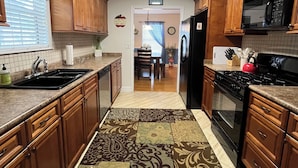 A kitchen with wooden cabinets, a black refrigerator, a stove, and a microwave.