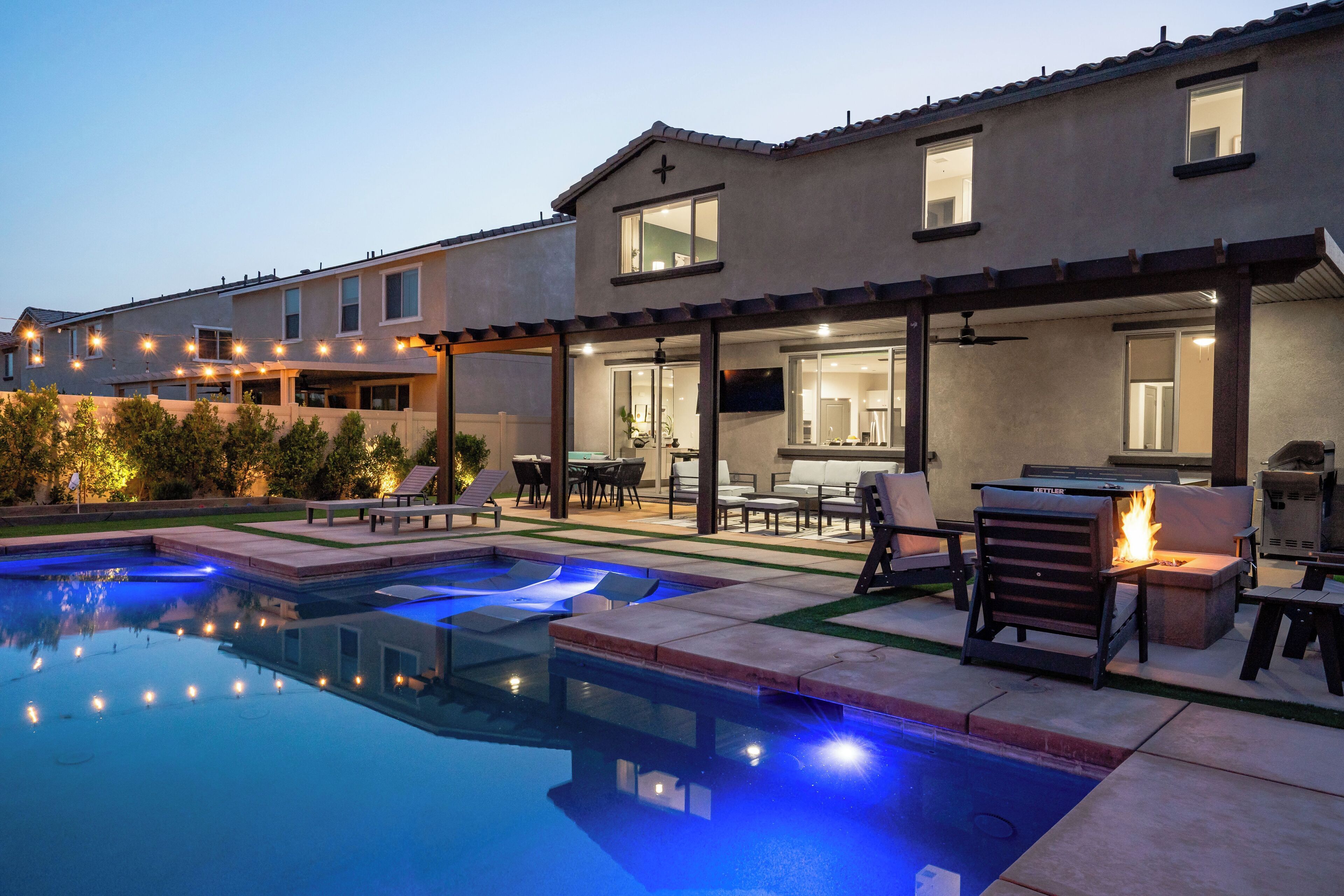 Une maison moderne dotée d’une piscine, d’un espace salon extérieur et d’un patio couvert.