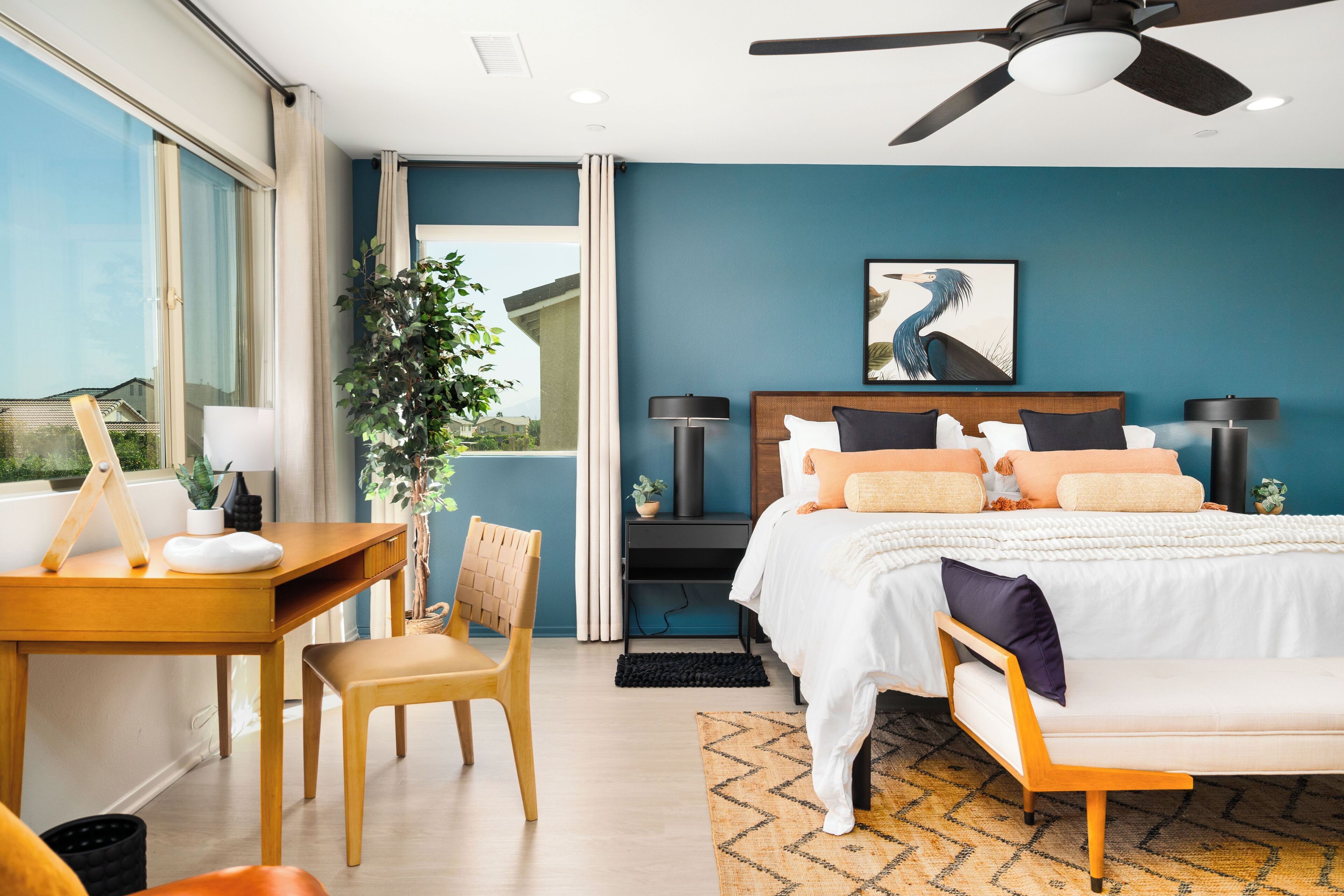 Une chambre à coucher comprenant un lit, un bureau, une chaise et un ventilateur de plafond.