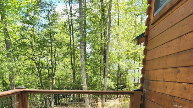 A hot tub on a wooden deck with a wooden cabin in the background. - Serenity at Nottely River (Murphy)