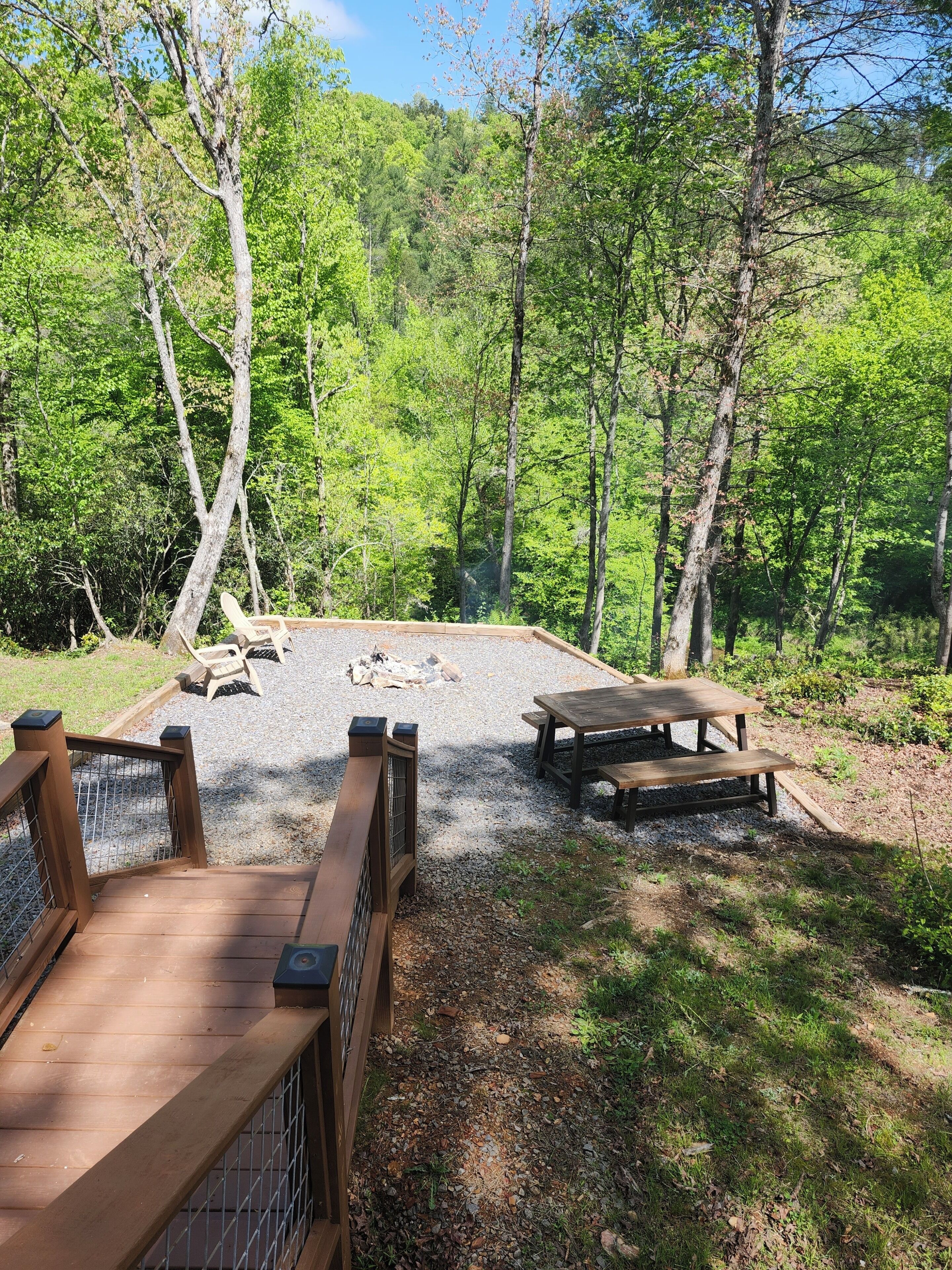 A picnic area with a wooden bench and picnic table surrounded by trees.