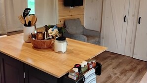 A kitchen with a wooden island, a grey sofa, and a TV mounted on the wall. - Serenity at Nottely River (Murphy)