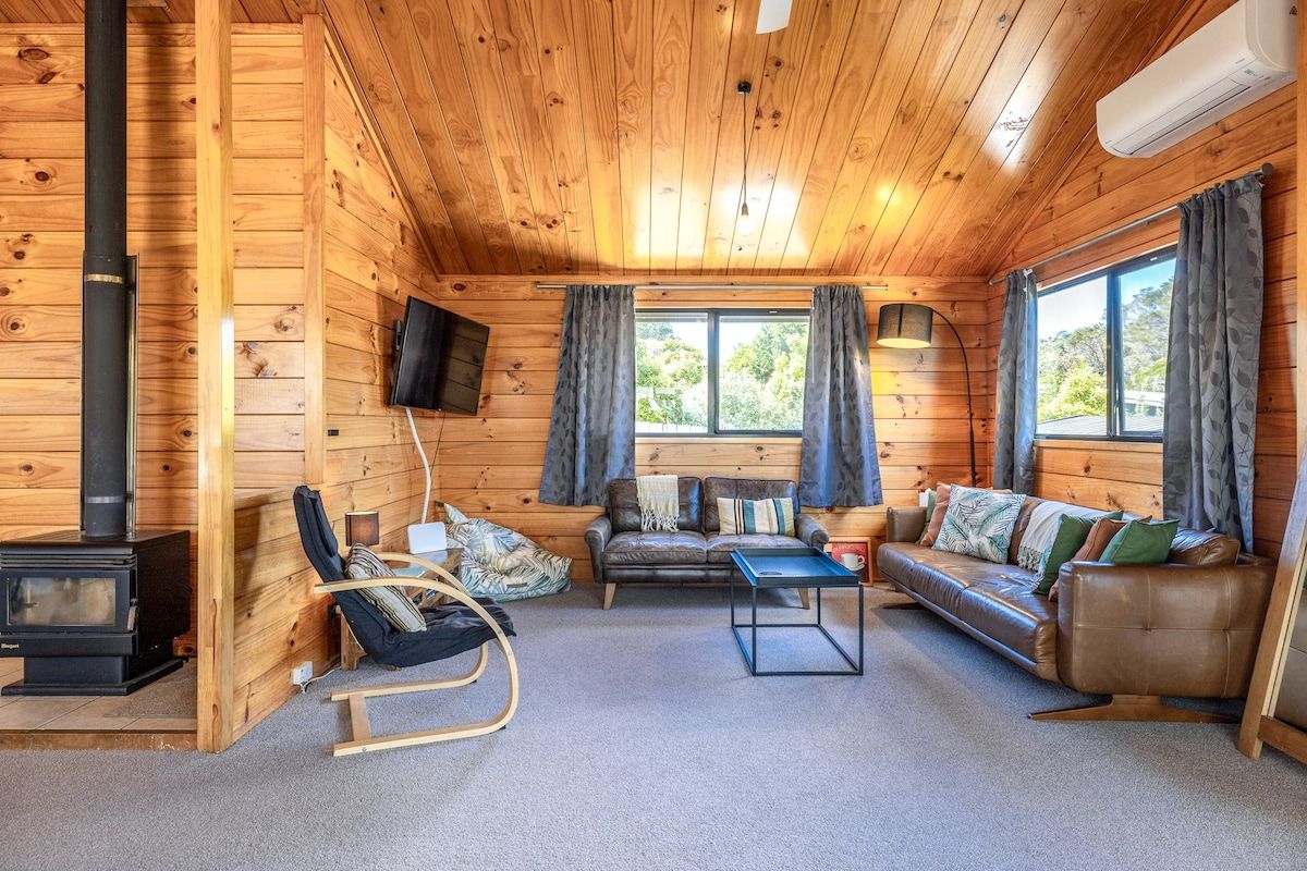 A cozy cabin interior with a fireplace, seating area, and large windows.