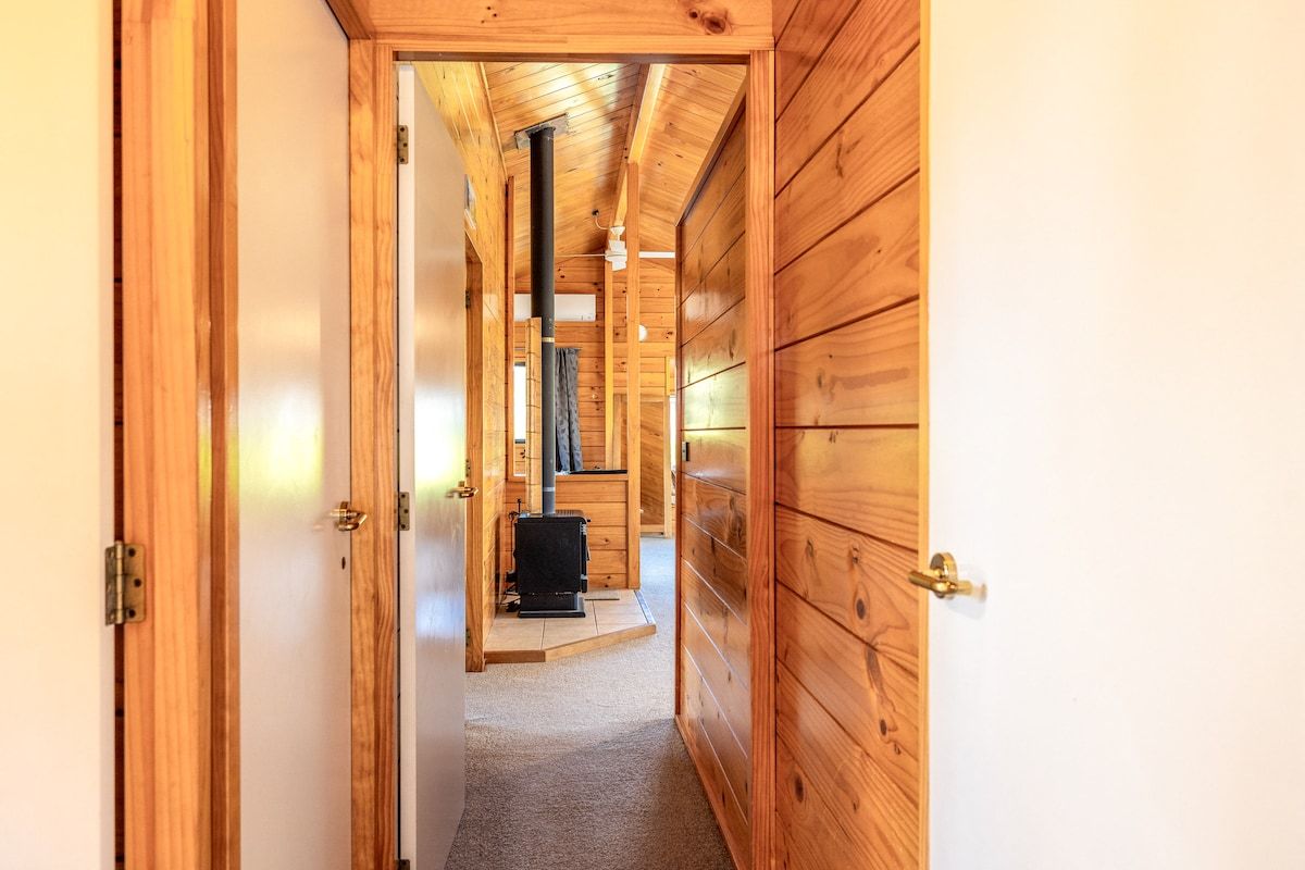 A wooden interior hallway leading to a room with a fireplace.