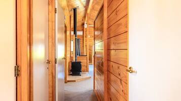 A wooden interior hallway leading to a room with a fireplace.