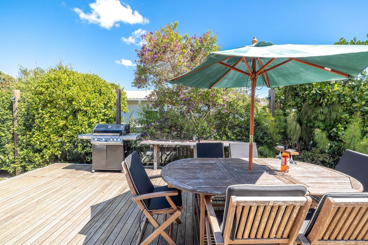 An outdoor patio with a wooden deck, a round table, and chairs.