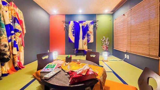 A room with a dining table, chairs, a ceiling fan, and a wall-mounted TV.