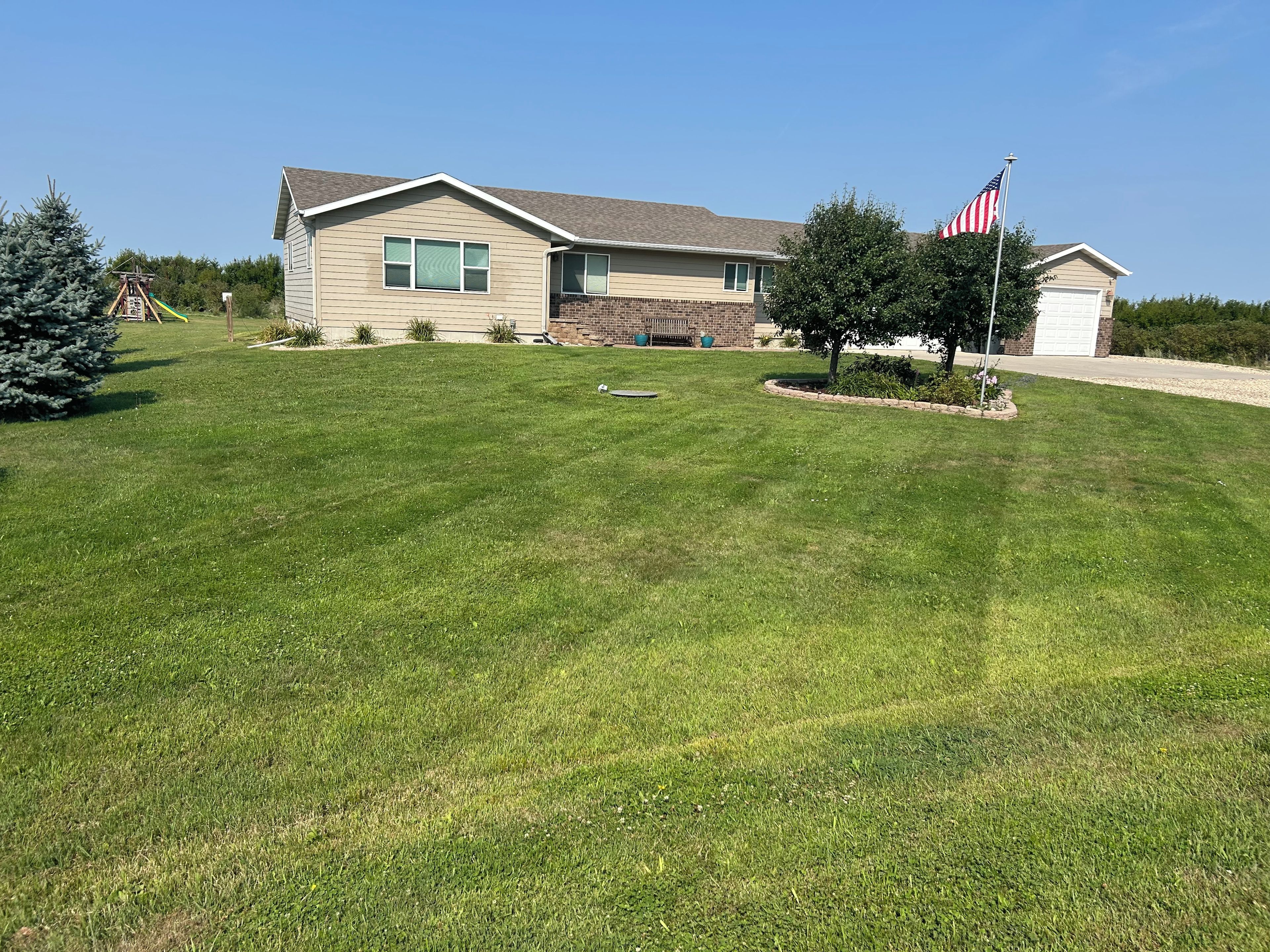 Ein Wohnhaus mit gepflegtem Rasen, einem Fahnenmast mit der US-amerikanischen Flagge und einer Ziegelgarage.