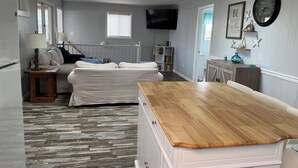 Amplia sala de estar con un gran sofá, una mesa de comedor de madera y un televisor montado en la pared.
