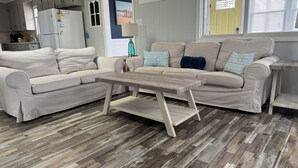 Una sala de estar moderna con un sofá color beige, una mesa de centro de madera y un suelo de madera con estampado tipo espiga.