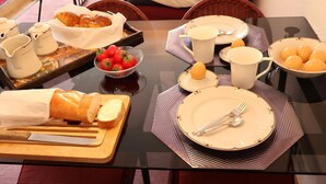 A dining table set with bread, strawberries, eggs, and utensils.