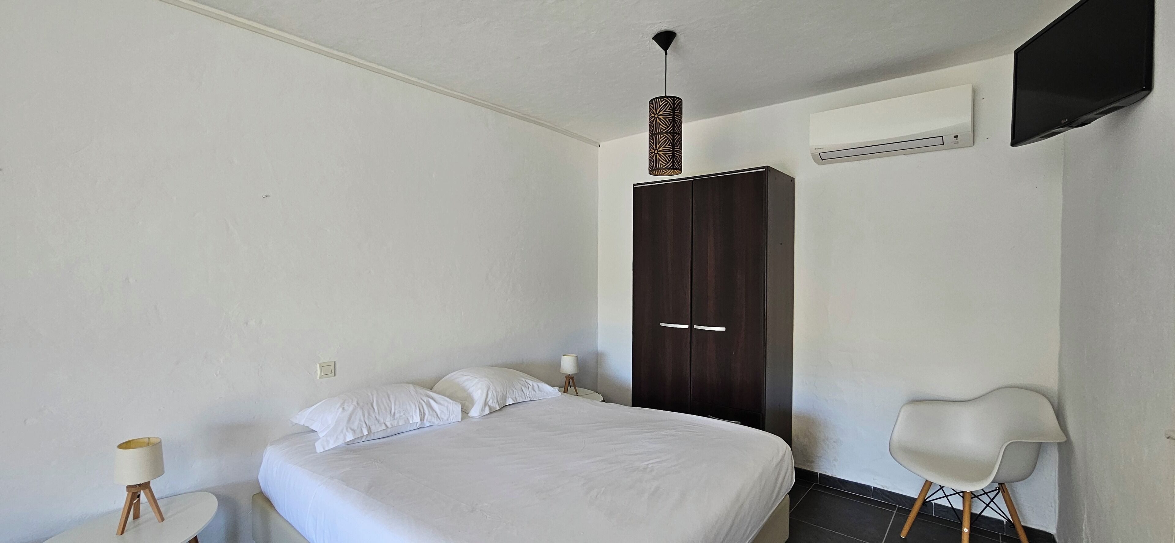 Een slaapkamer met een bed, een kast, een stoel en een lamp.