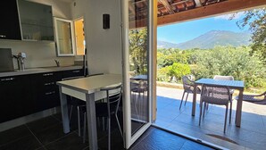 Een moderne keuken met een schuifdeur naar een terras buiten, compleet met een tafel en stoelen.