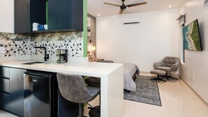A modern kitchen with a white countertop, black cabinets, and a dishwasher. There is a ceiling fan and a painting on the wall. - Private Tropical Villa with Backyard • Pool • Fast WiFi • Self Check-In (Provincia de Guanacaste)