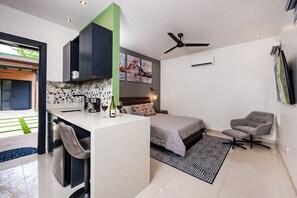 A modern bedroom with a bed, a desk, a chair, and a ceiling fan.